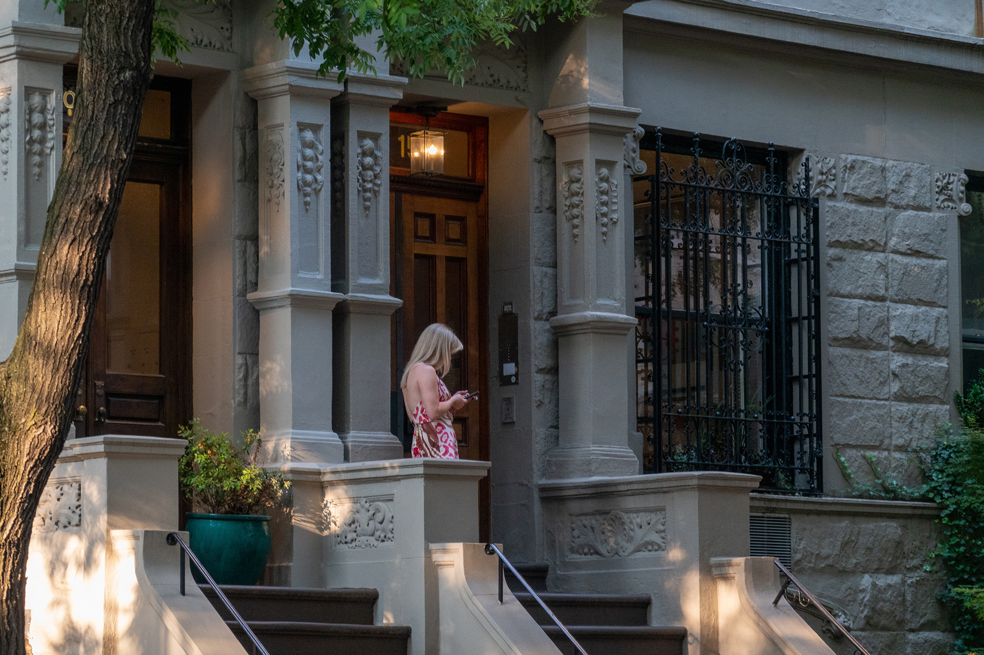 Christoph Radke, New York City, woman at front door texting, 2022